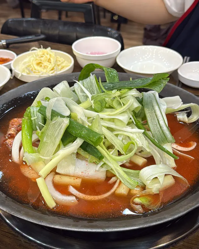 물닭갈비가 담긴 냄비 위에 파와 양파가 수북하게 올려져 있다.