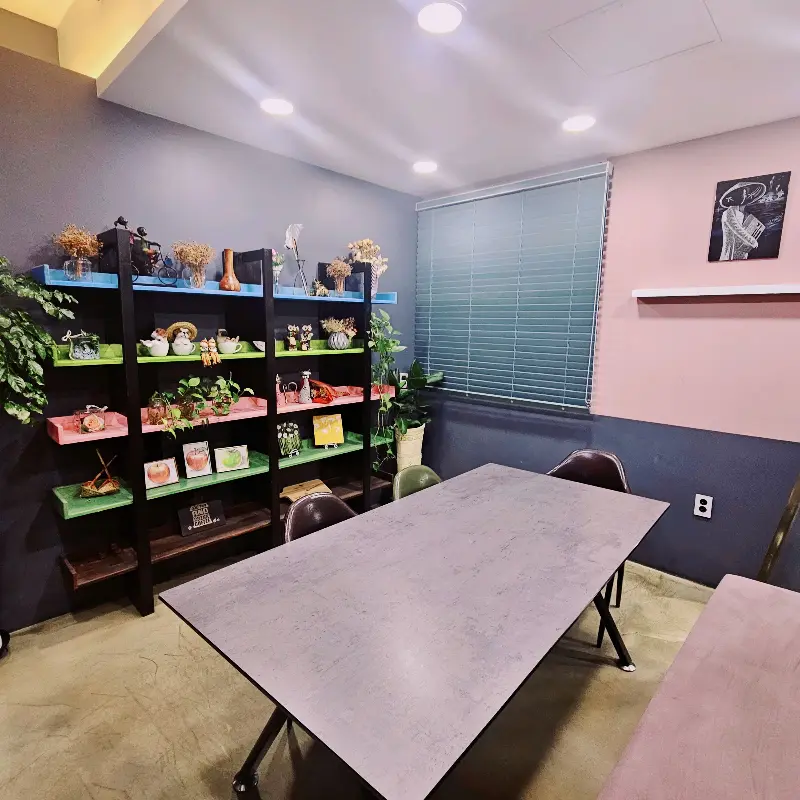 카페 내부, 테이블과 의자가 놓여 있고, 벽면에는 장식품들이 진열되어 있다.