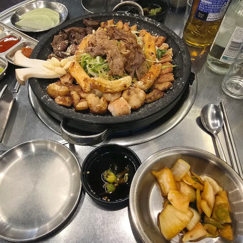 모듬 곱창이 거의 다 먹어갈 때쯤, 불판 위에 떡 구이가 올려져 있다. 떡은 노릇노릇하게 구워져 있고, 위에는 하얀 치즈 가루가 뿌려져 있다.