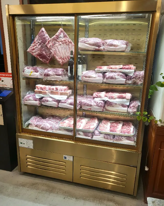 뚱딴지 가게 내부에 고기 숙성고가 있으며, 다양한 부위의 고기가 진열되어 있는 모습