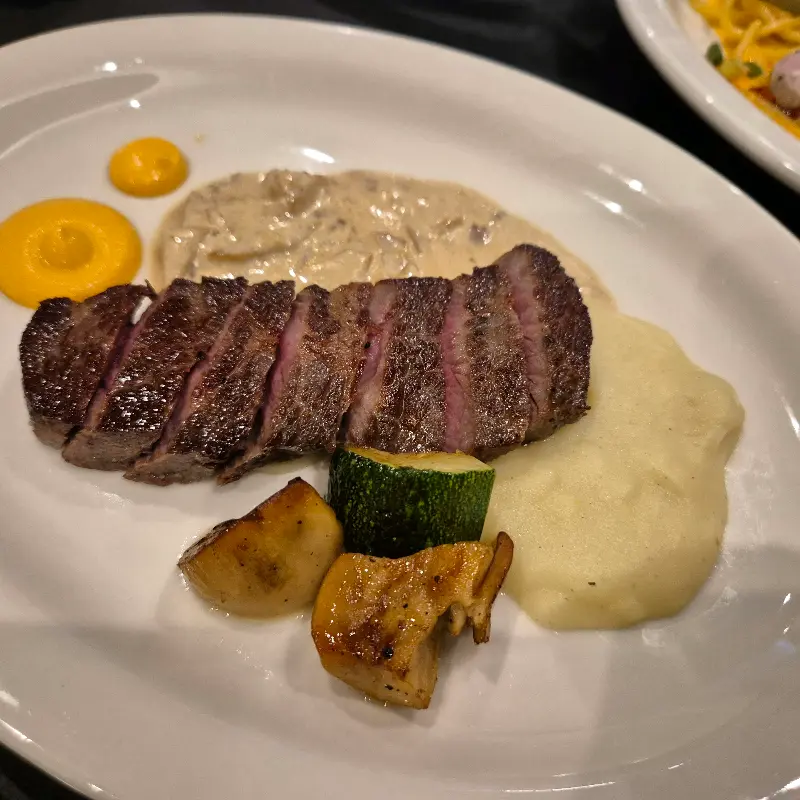 잘 구워진 살치살 스테이크와 곁들여진 야채, 그리고 소스