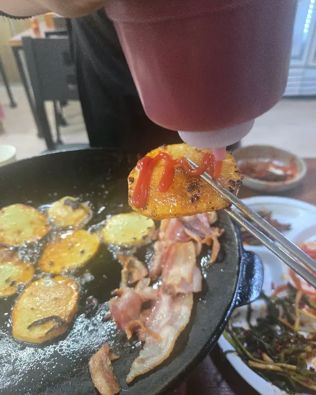 구워진 감자에 케첩을 뿌리는 모습