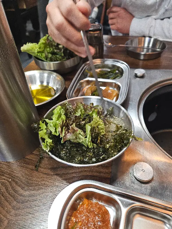 잘 구워진 고기를 쌈에 싸서 먹는 모습