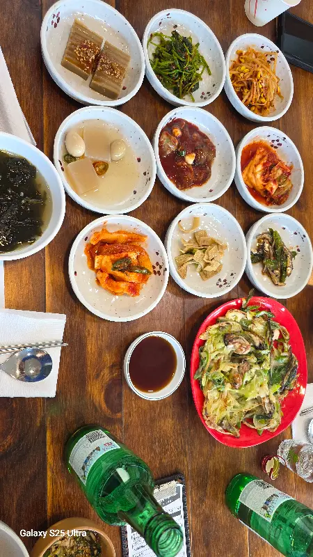 다양한 반찬과 파전, 막걸리 병이 함께 놓인 식탁