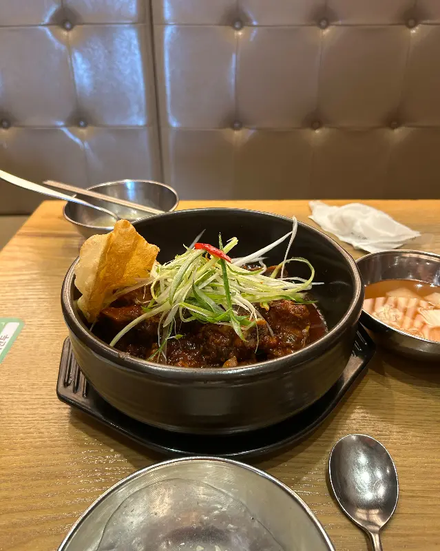 갈비찜 위에 파와 납작만두가 올려져 있는 모습