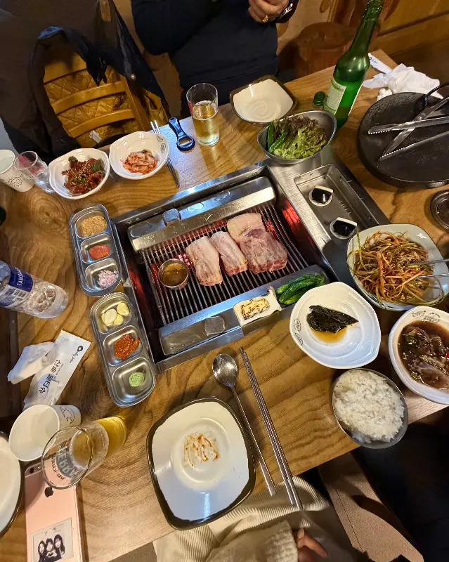 불판 위에서 맛있게 익어가는 흑돼지 근고기, 전복, 버섯, 꽈리꼬추의 모습