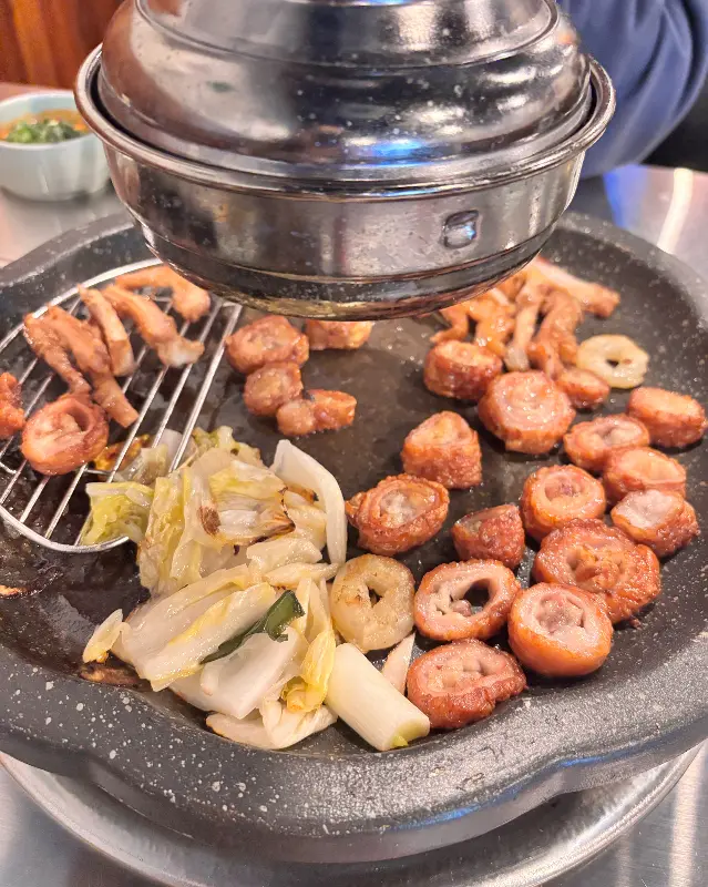 불판 위에 막창, 김치, 양파를 함께 구워먹는 모습
