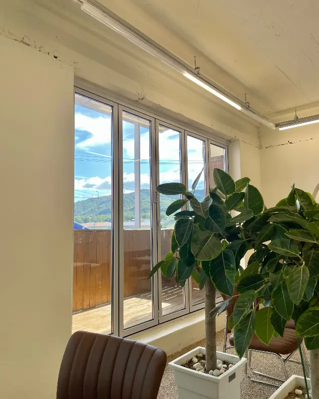 창밖으로 푸른 하늘과 산이 보이는 카페 내부