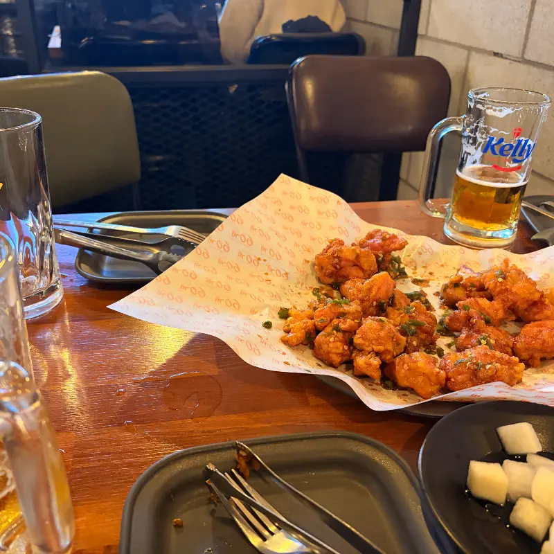 나무 테이블 위에 놓인 고추치킨과 맥주