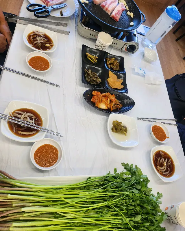 테이블 가득 차려진 밑반찬과 미나리 삼겹살
