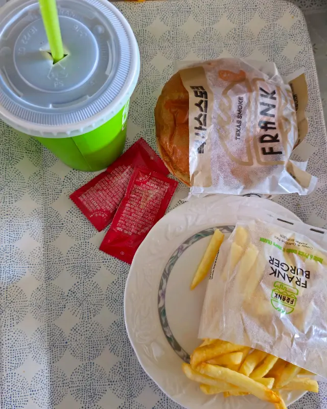 접시에 담겨 나온 프랭크버거, 감자튀김, 음료
