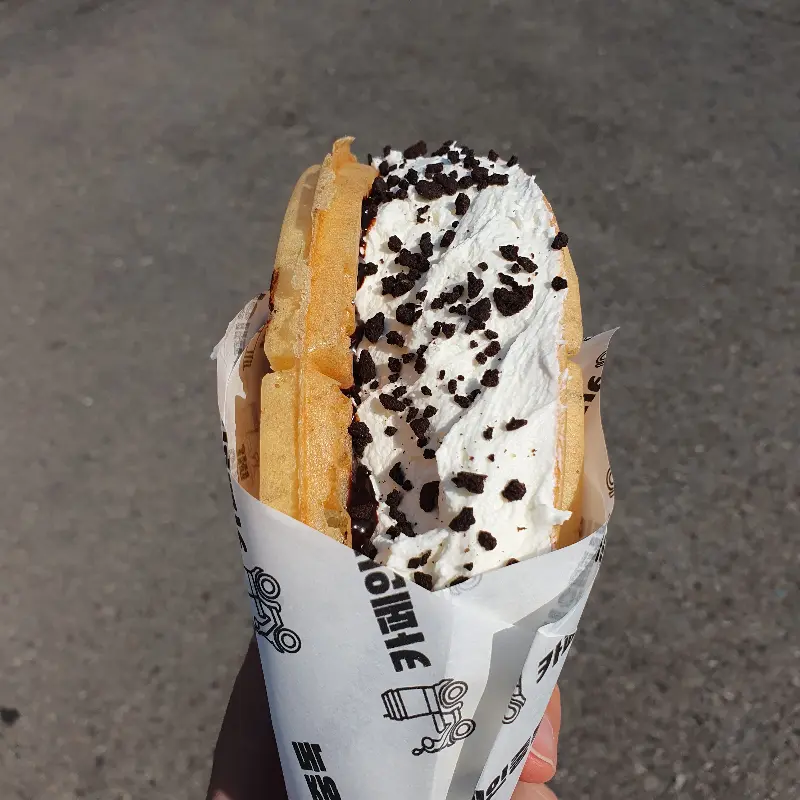 손에 들려진 와플, 크림과 초코칩이 듬뿍 올려져 있다.