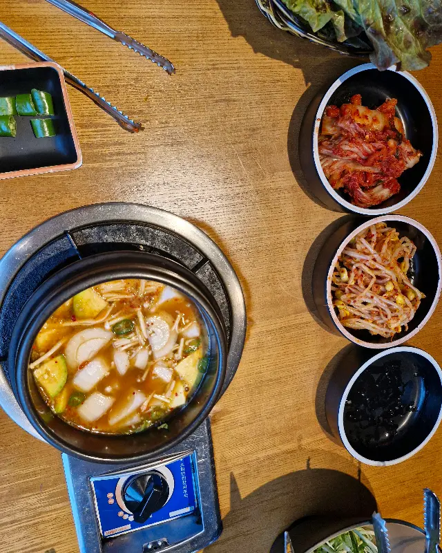 테이블 중앙에 놓인 뚝배기에 담긴 김치찌개의 모습