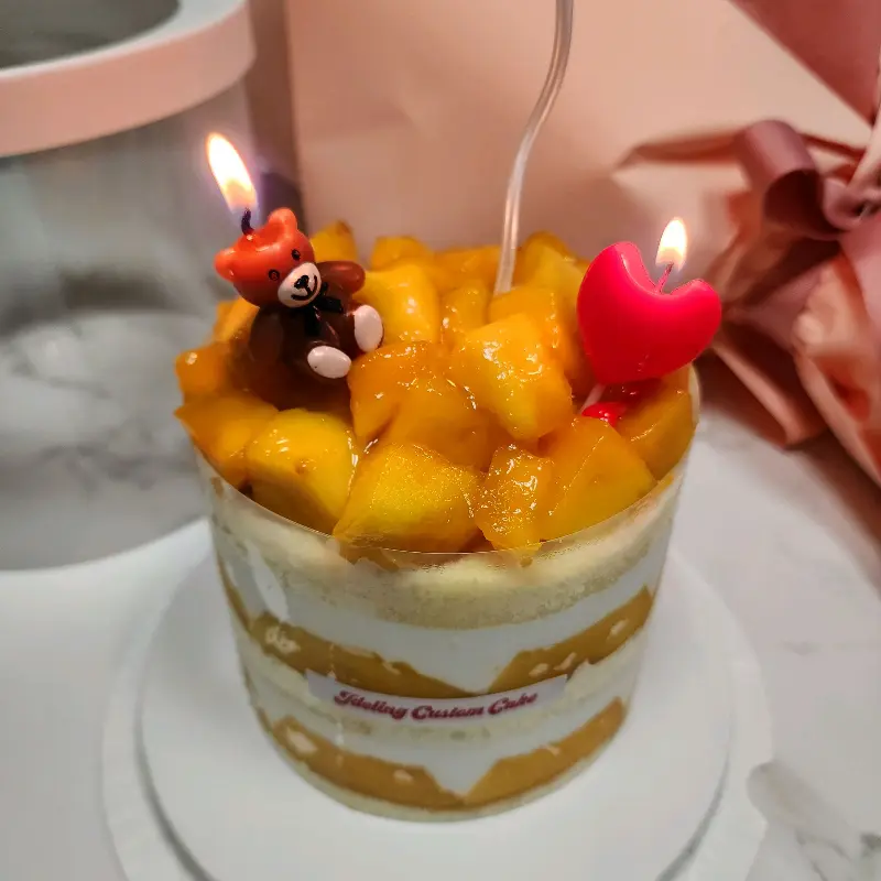 케이크 위에 곰돌이 모양 초와 하트 모양 초를 꽂은 모습