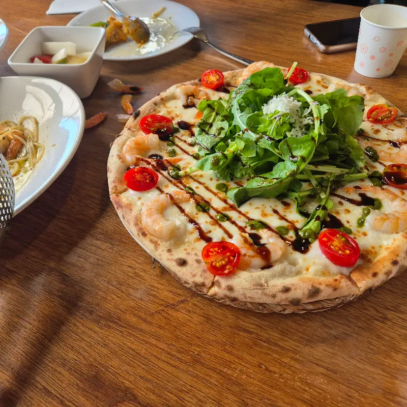 테이블 위에 놓인 피자와 파스타, 피클의 모습. 푸짐한 한 상 차림이다.