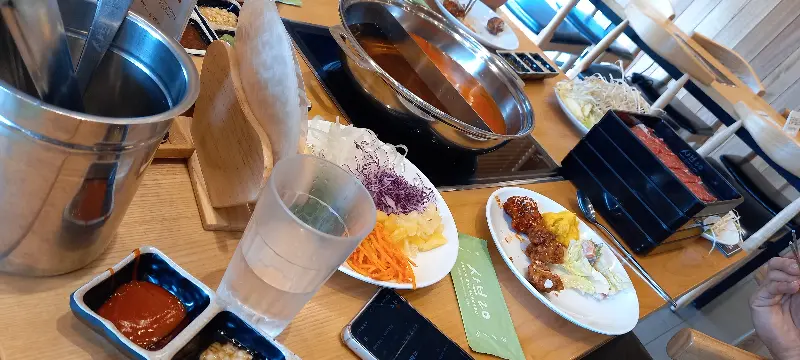 테이블 위에 놓인 샤브샤브 냄비와 다양한 소스