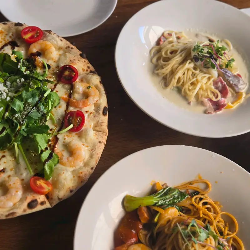 피자와 파스타, 샐러드가 함께 놓인 테이블 사진. 풍성한 식탁이 인상적이다.