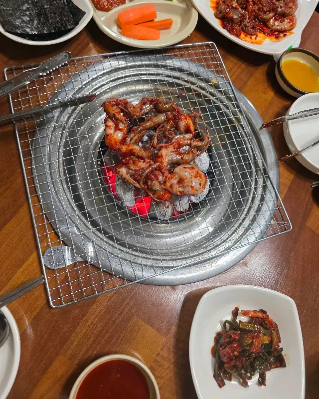 숯불 위에 올려진 쭈꾸미와 기본 반찬