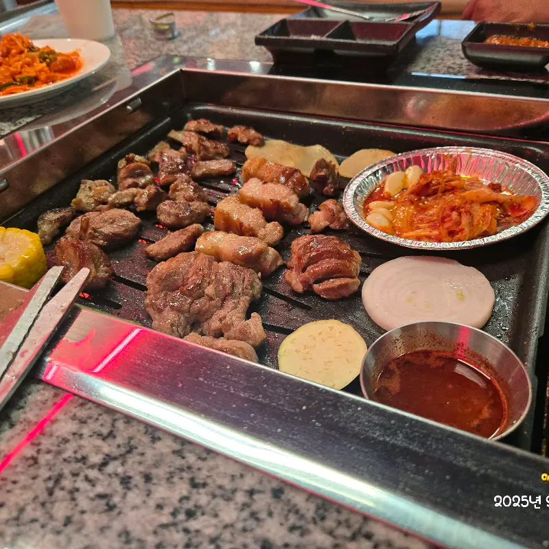 고기, 김치, 양파 등이 불판 위에 놓여 있는 모습