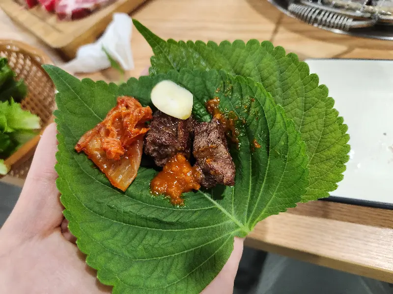잘 구워진 소고기를 깻잎에 싸서 먹는 모습