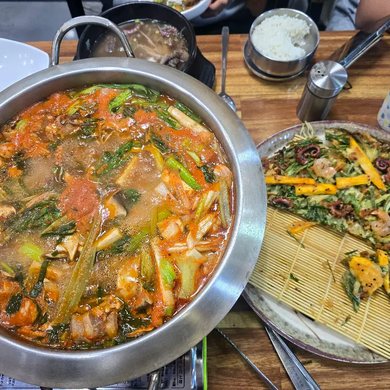 낙곱새 전골과 해물파전, 밥이 함께 놓인 테이블 전체샷