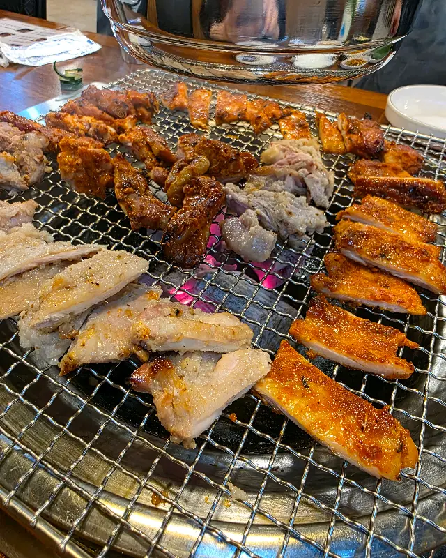 숯불 위에서 맛있게 익어가는 다양한 종류의 닭갈비