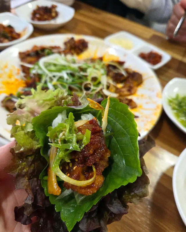 흑돼지 석쇠구이를 쌈에 싸서 먹는 모습