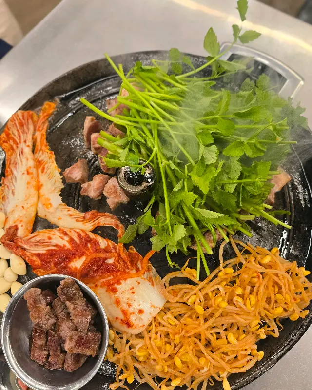 미나리, 김치, 콩나물과 함께 구워지는 삼겹살