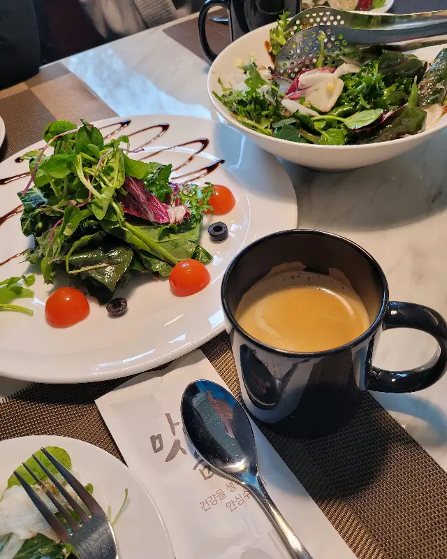 테이블 위에 놓인 스테이크 샐러드와 커피