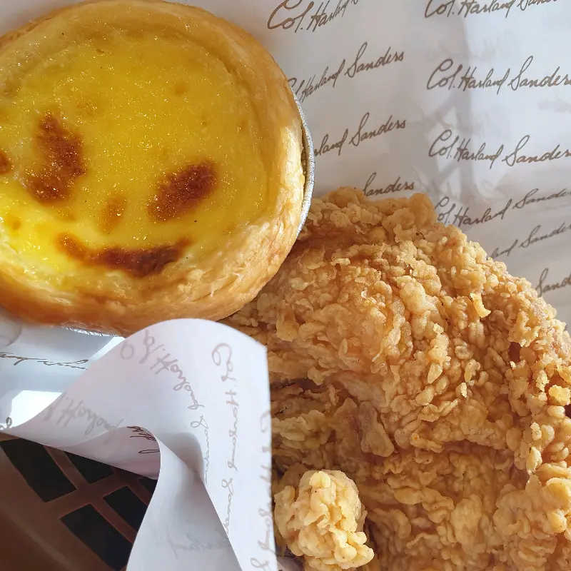 KFC 에그타르트와 핫크리스피 치킨의 클로즈업 샷. 에그타르트의 노란 커스터드 크림이 먹음직스럽다.