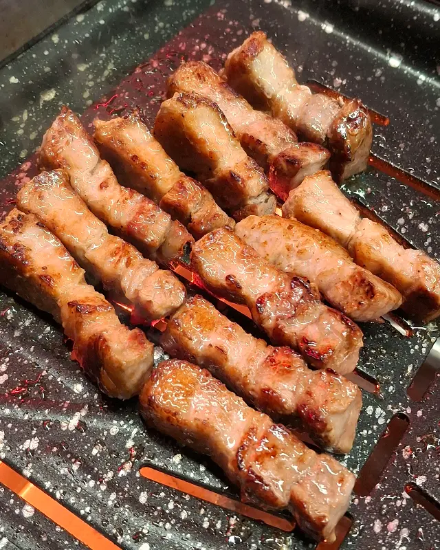 초벌된 삼겹살이 먹기 좋게 잘려 불판에 가지런히 놓여 있는 모습