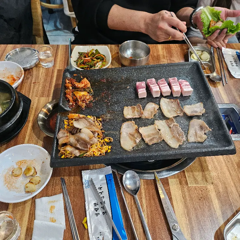 흑돼지 오겹살을 쌈에 싸서 먹는 모습