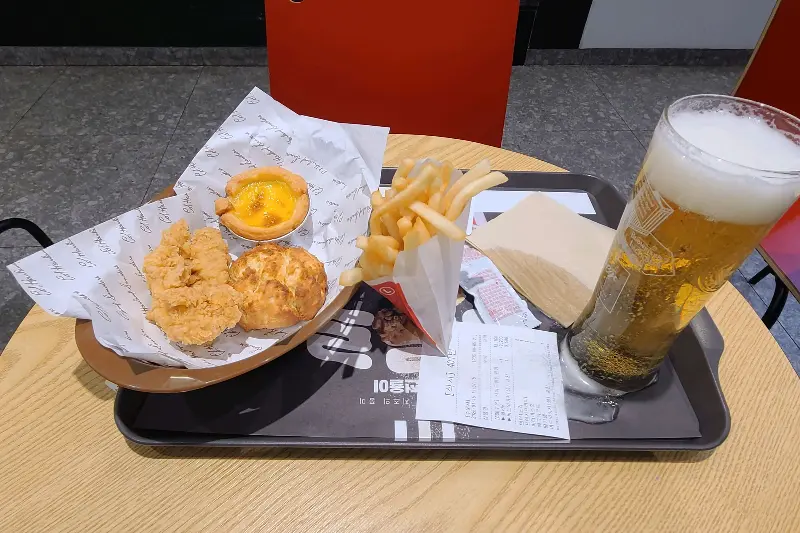 쟁반 위에 놓인 KFC 메뉴들. 에그타르트, 비스켓, 감자튀김, 맥주가 보인다.