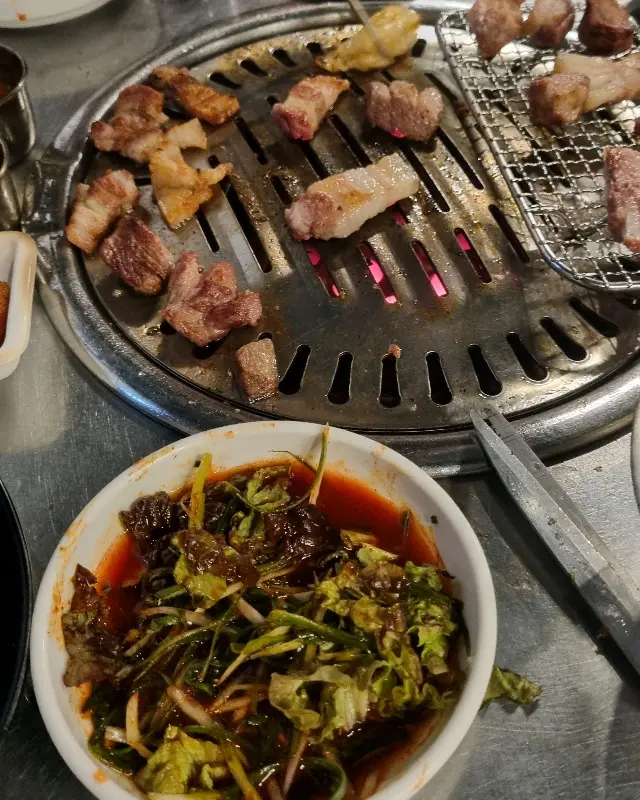 잘 익은 흑돼지 한 점과 쌈 채소가 놓여 있다.