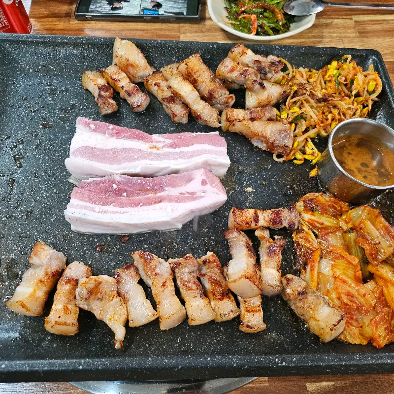 숯불 위에서 노릇하게 익어가는 흑돼지 오겹살과 밑반찬