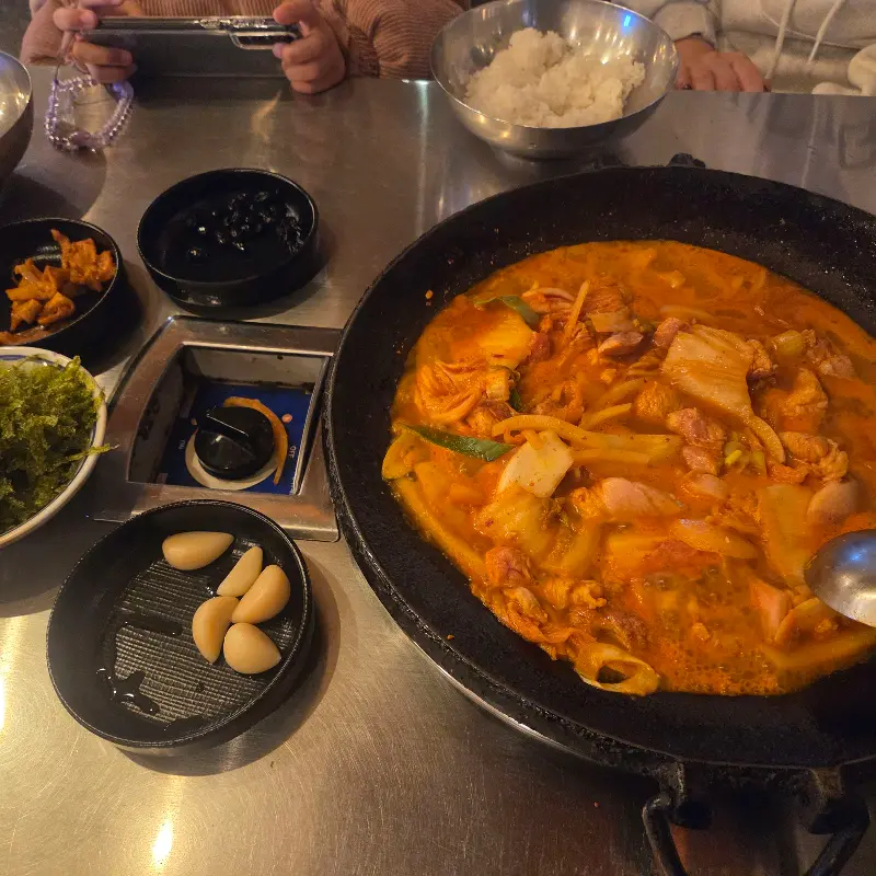 테이블 위에 김치찌개와 밥, 반찬 등이 놓여있다.