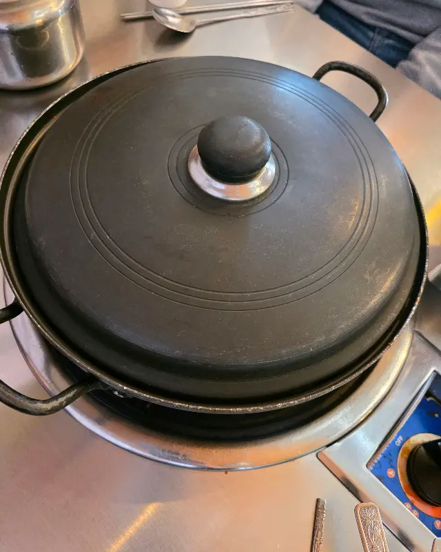 검은 냄비 뚜껑이 덮인 김치찌개