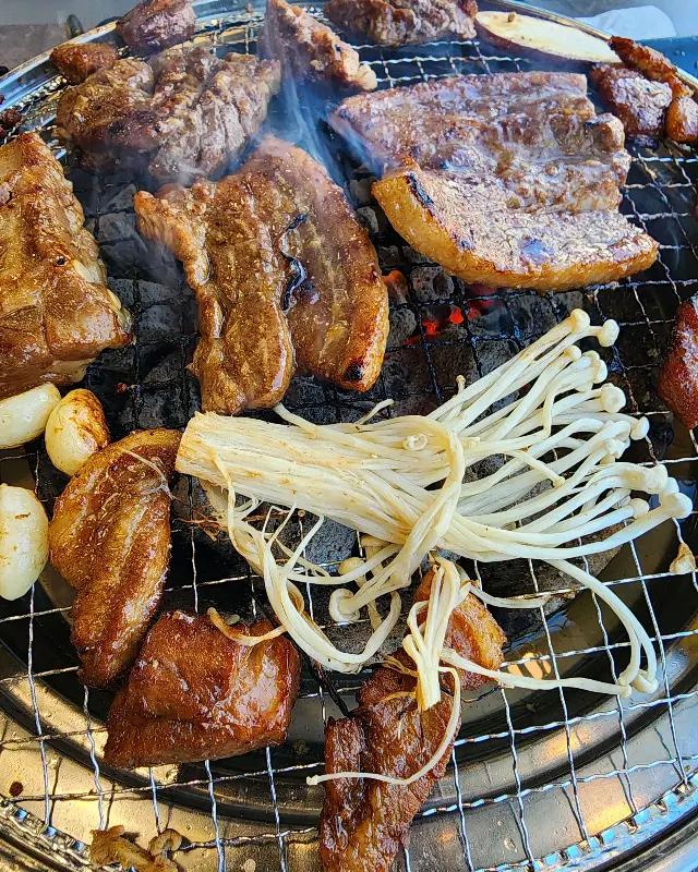 숯불 위에서 맛있게 익어가는 돼지갈비와 버섯