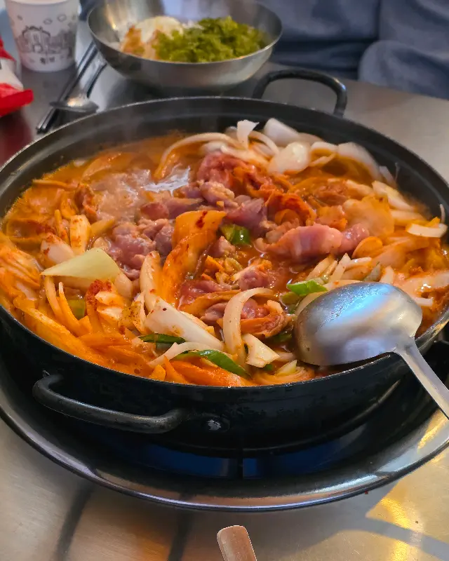 김치찌개에 돼지고기, 김치, 양파 등이 푸짐하게 들어있다.