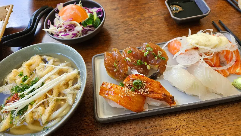 다양한 종류의 초밥이 담긴 접시와 샐러드, 우동