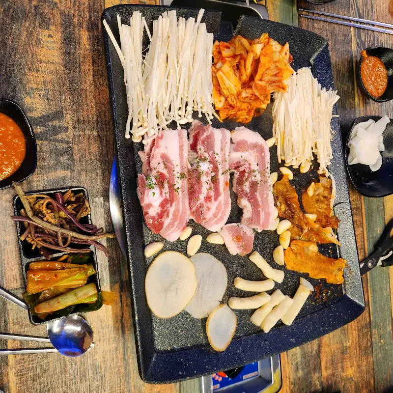 불판 가득 구워진 대패삼겹살과 다양한 재료들