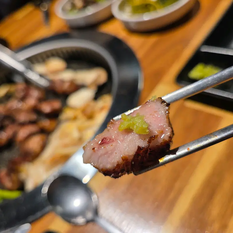 잘 구워진 목살 한 점을 젓가락으로 집어 올린 모습