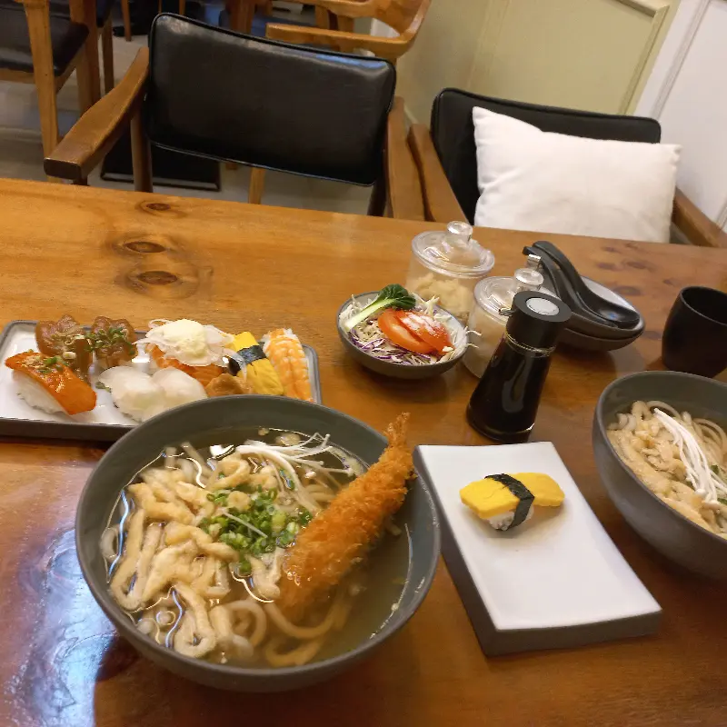 테이블 위에 놓인 초밥, 샐러드, 우동