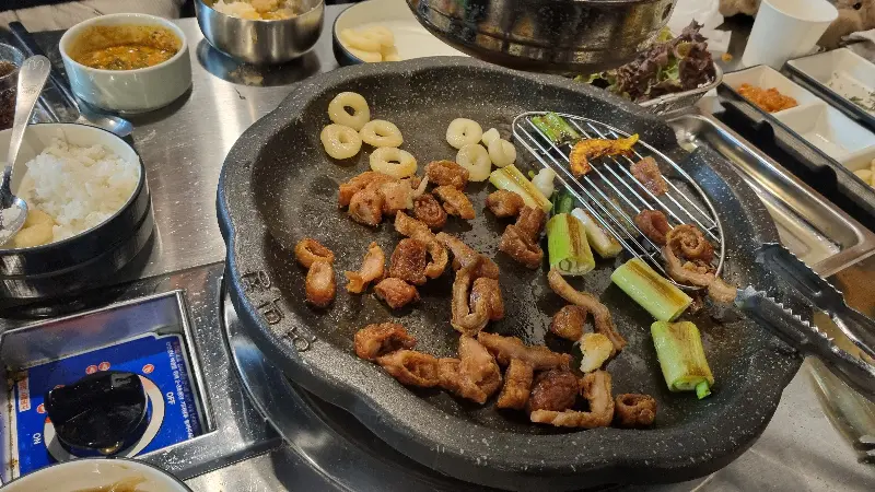 불판 위에 막창과 다양한 채소가 함께 놓여있는 모습