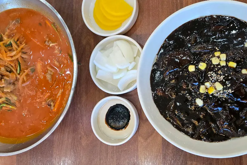 짬뽕, 짜장면, 단무지, 양파가 놓인 테이블 사진