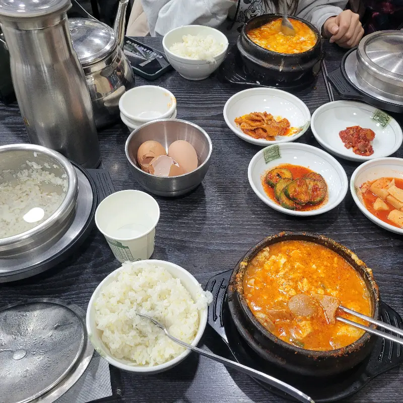 테이블 가득 차려진 순두부찌개와 반찬들의 모습