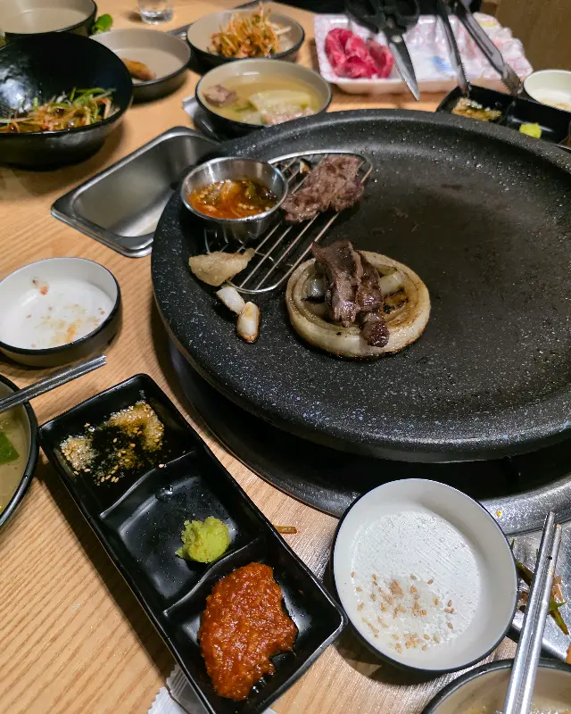 불판 위에서 익어가는 고기와 밑반찬