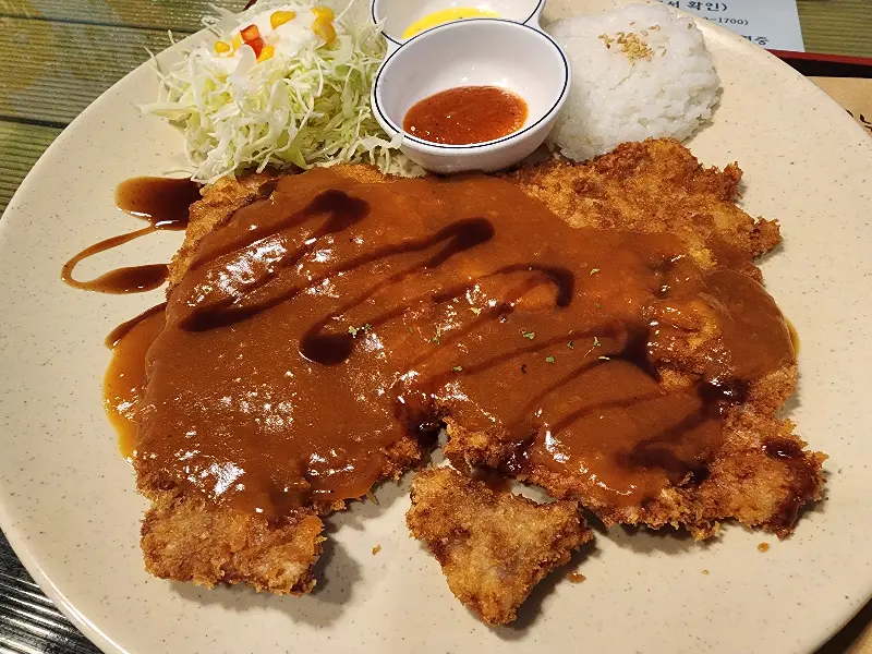 두툼한 돈까스 위에 윤기가 흐르는 소스가 듬뿍 뿌려져 있다.