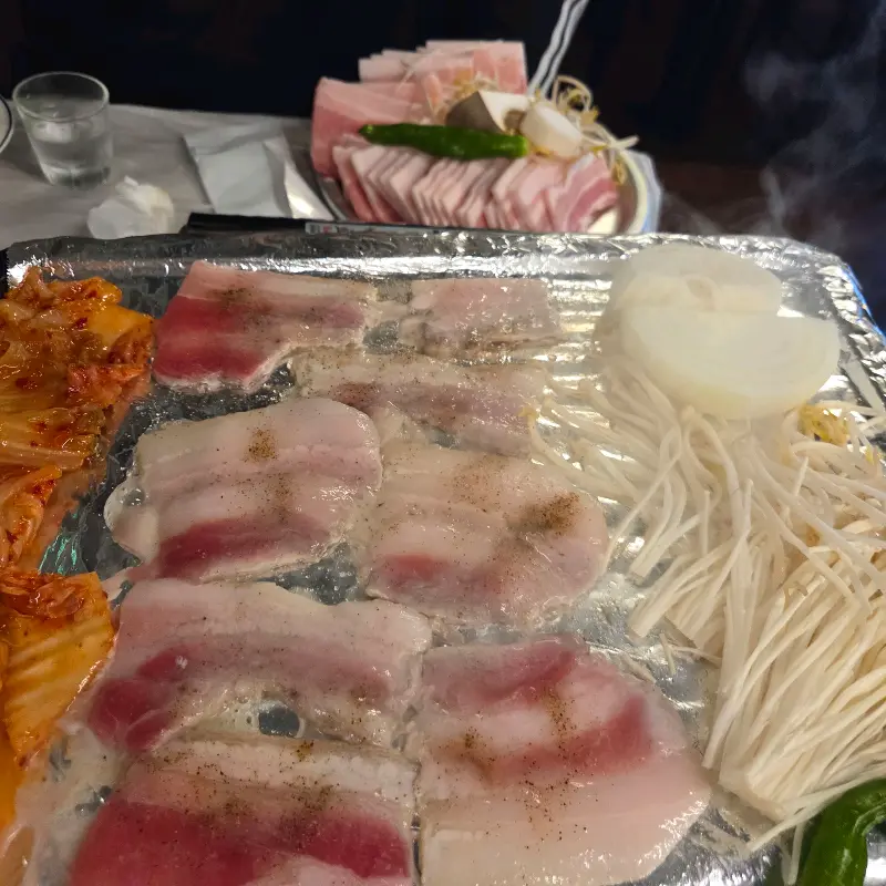 불판 위에서 김치와 함께 익어가는 냉동 삼겹살