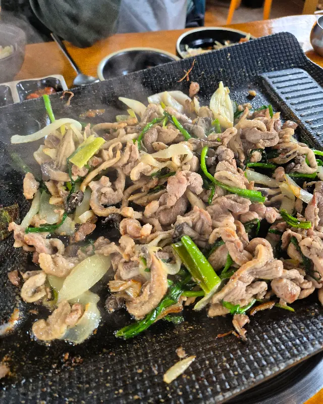 불판 위에서 맛있게 익어가는 오리 로스와 채소들